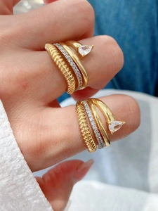 Dettaglio di anelli multistrato placcati oro 18K con zirconi e pietra a forma di pera