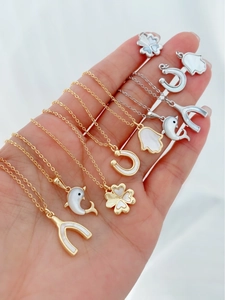 Detail van 18K gouden en zilveren hangers met parelmoer klavers en dolfijnen