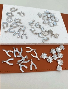 Macro-opname van dolfijn en klaver hangers met parelmoer inleg voor DIY sieraden maken