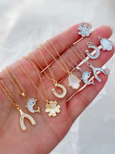 Macroshot van 18K goud en zilver dolfijn klaver hangers met wit parelmoer ingelegde details