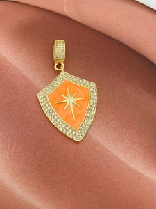 Makroaufnahme: Goldener Schildanhänger mit orangem Emaille-Stern und Zirkonia-Rand