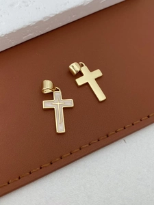 Detailopname van twee gouden kruishangers met wit emaille op bruin lederen ondergrond