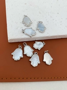 Macro-opname van zilveren Hamsa-hangers met wit parelmoer inleg voor DIY-sieraden