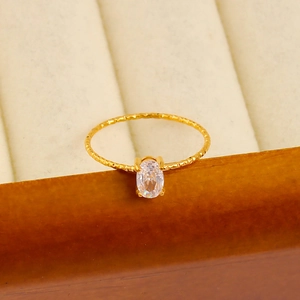 Detail of 18K gold-plated ring with oval zircon on a wooden jewelry box edge