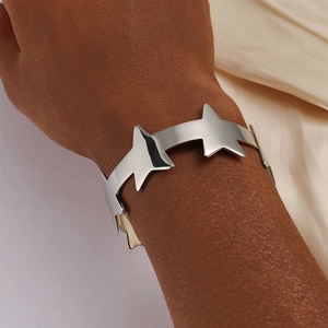 Macro-opname van een zilveren roestvrijstalen open sterarmband gedragen op de pols nu