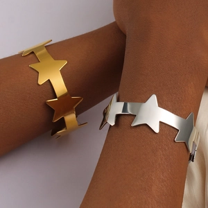 Detailweergave van gepolijste 18K gouden en zilveren ster open armbanden om de pols