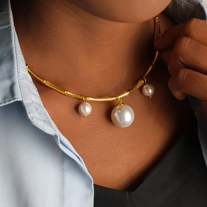 Gros plan d'un collier choker doré style bambou avec trois perles blanches dégradées