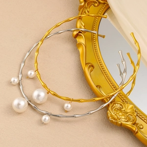 Détail de colliers rigides en bambou doré et argenté avec pendentifs en perles fines