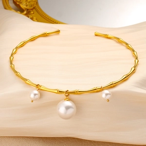 Détail du collier rigide bambou doré avec trois pendentifs en perles blanches