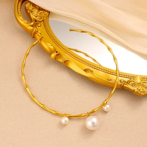 Détail macro du collier à maillons de bambou doré avec trois pendentifs en perles blanches