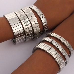 Detail view of various textured stainless steel stretch bracelets on a model's wrist