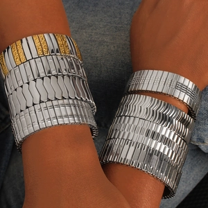 Detail of elastic stainless steel bracelets with embossed textures on denim background