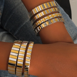 Detailed macro of two-tone stainless steel stretch bracelets on denim background