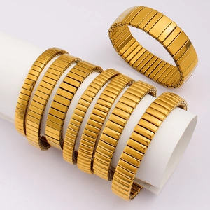 Polished gold stretch band bracelet in stainless steel watch strap style on a white stand