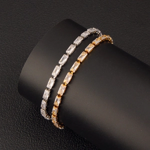 Macro view of gold and silver tennis bracelets with emerald-cut cubic zirconia on black stand