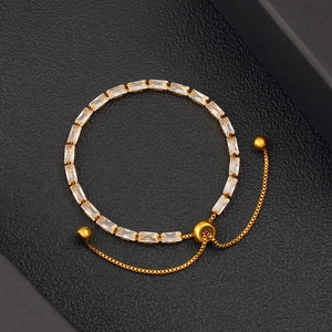 Macro shot of adjustable gold-plated bracelet with rectangular zircon stones on black leather