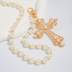 Detail of gold hollow cross pendant with pearls and a metal lobster clasp on a chain