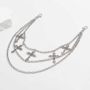 Detail of triple-layer silver metal pants chain with gothic cross pendants on white stone