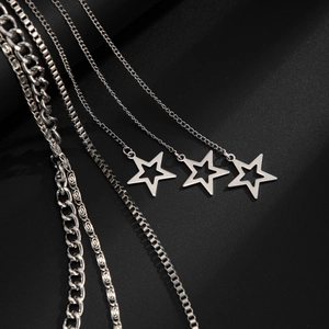 Detail showing multi-layered silver cuban link, box chains, and star pendants on black