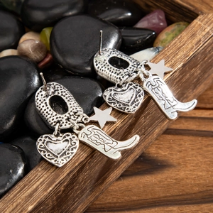 Primer plano detallado de los pendientes estilo cowboy con botas y estrellas
