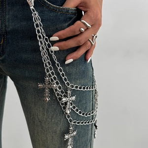 Close-up of multi-layer hip hop silver cross pendants and metal chains on blue jeans