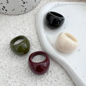 Close-up of colorful resin rings in olive green, burgundy, black, and cream with glossy finish