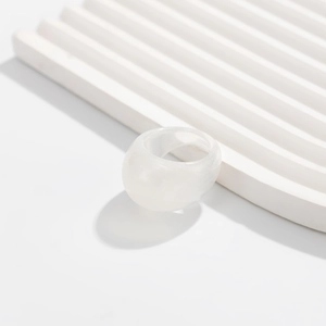 Detail view of the wide translucent white resin ring with a glossy smooth acrylic finish