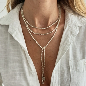 Drielaagse kralenketting met Y-hanger en onregelmatige metalen druppels op een shirt