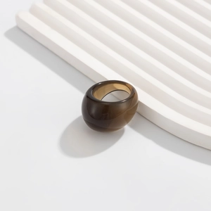 Macro shot of minimalist translucent amber resin ring on wave textured display stand