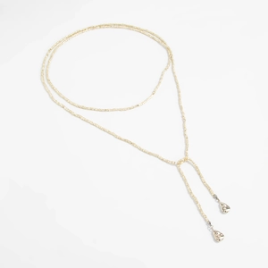 Detail van een lange kralenketting met metalen druppelhangers en gouden imitatieparels