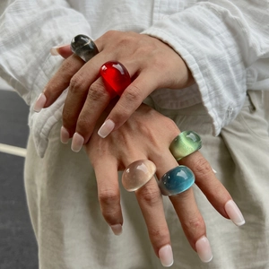 Close-up of hand wearing colorful ice-textured resin rings in diverse trendy shades