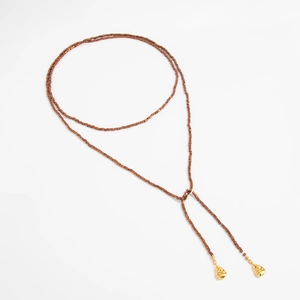 Detail van een lange kralenketting met metalen hangers en bronzen vierkante kralen