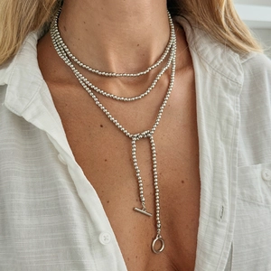Detail van zilveren gelaagde kralenketting met metalen schijfjes en T-bar sluiting