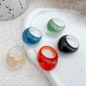 Close-up of colorful translucent resin rings in blue, green, and orange on a ceramic tray