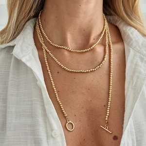 Gedetailleerde close-up van meerlaagse gouden kralenketting met een elegante OT-kneelsluiting