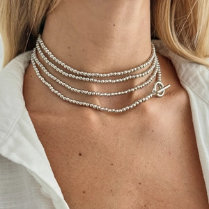 Detail van een meerlaagse zilveren kralenketting met een gepolijste OT-kapittel sluiting