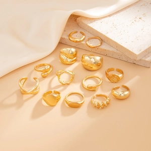 Detailed macro view of assorted golden liquid metal rings on beige travertine background