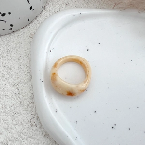 Detailed shot of cream marble resin ring displayed on a minimalist ceramic tray