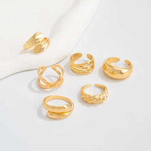 Detail of six-piece gold ring set featuring minimalist smooth and twisted textured designs