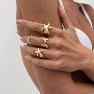 Goldenes Ozean-Ring-Set mit Seestern- und Muschelmotiven an der Hand eines Modells