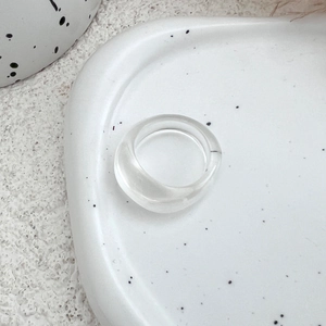 Close-up of a clear acrylic resin ring on a minimalist black-spotted white tray