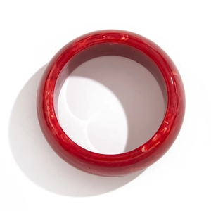Detail of a deep red acrylic bangle with unique white swirl textures and smooth finish