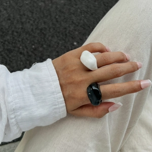 Detail view of chunky irregular resin rings in glossy black and white finish on hand