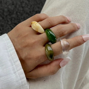 Set of four translucent and marbled colorful resin rings on hand in a stylish minimalist pose