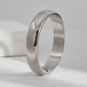 Polished silver metal bangle with a hinge and clasp closure on white stone surface