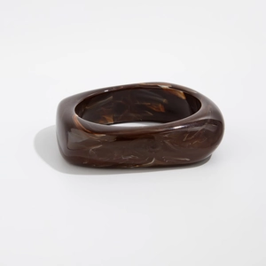 Close-up of retro wide tortoiseshell resin bangle with marbled amber texture