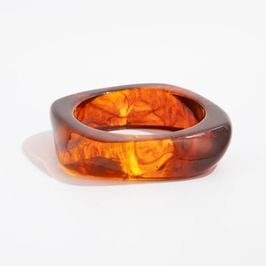 Macro detail of amber resin bangle showing translucent ink dye and gold foil texture