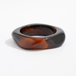 Detailed macro view of wide amber resin bangle with dark tortoiseshell texture