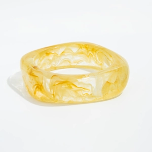 Detail view of transparent amber acrylic cuff with unique marble texture and gold foil