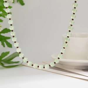 Vue macro d'un collier de perles en verre vert clair translucide avec petits séparateurs